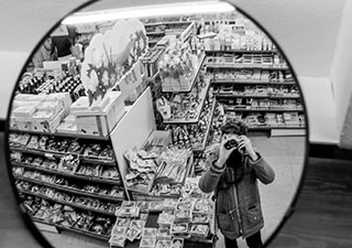 Schwarzweißfoto aus den 80ern, Fotograf spiegelt sich selbst im Beobachtungsspiegel des Supermarktes